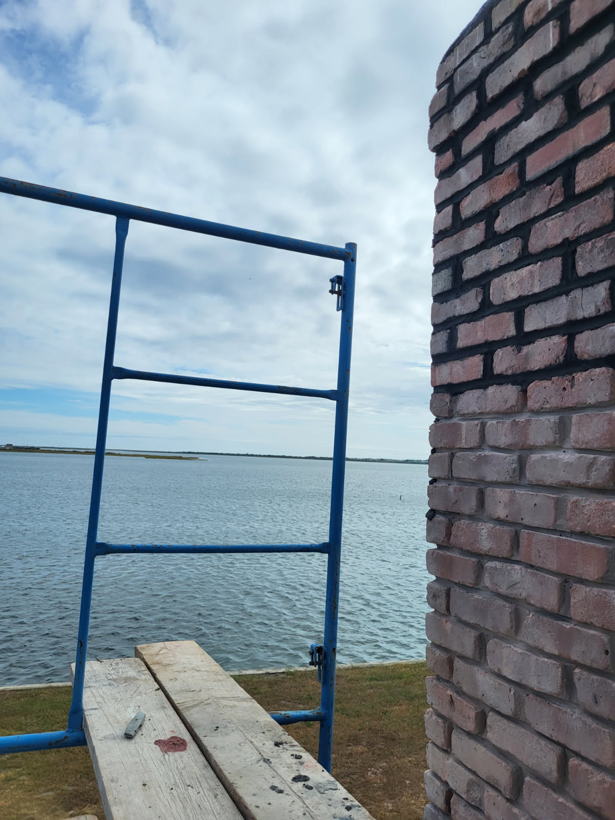 Newly laid brick chimney masonry beside scaffolding at a waterfront property