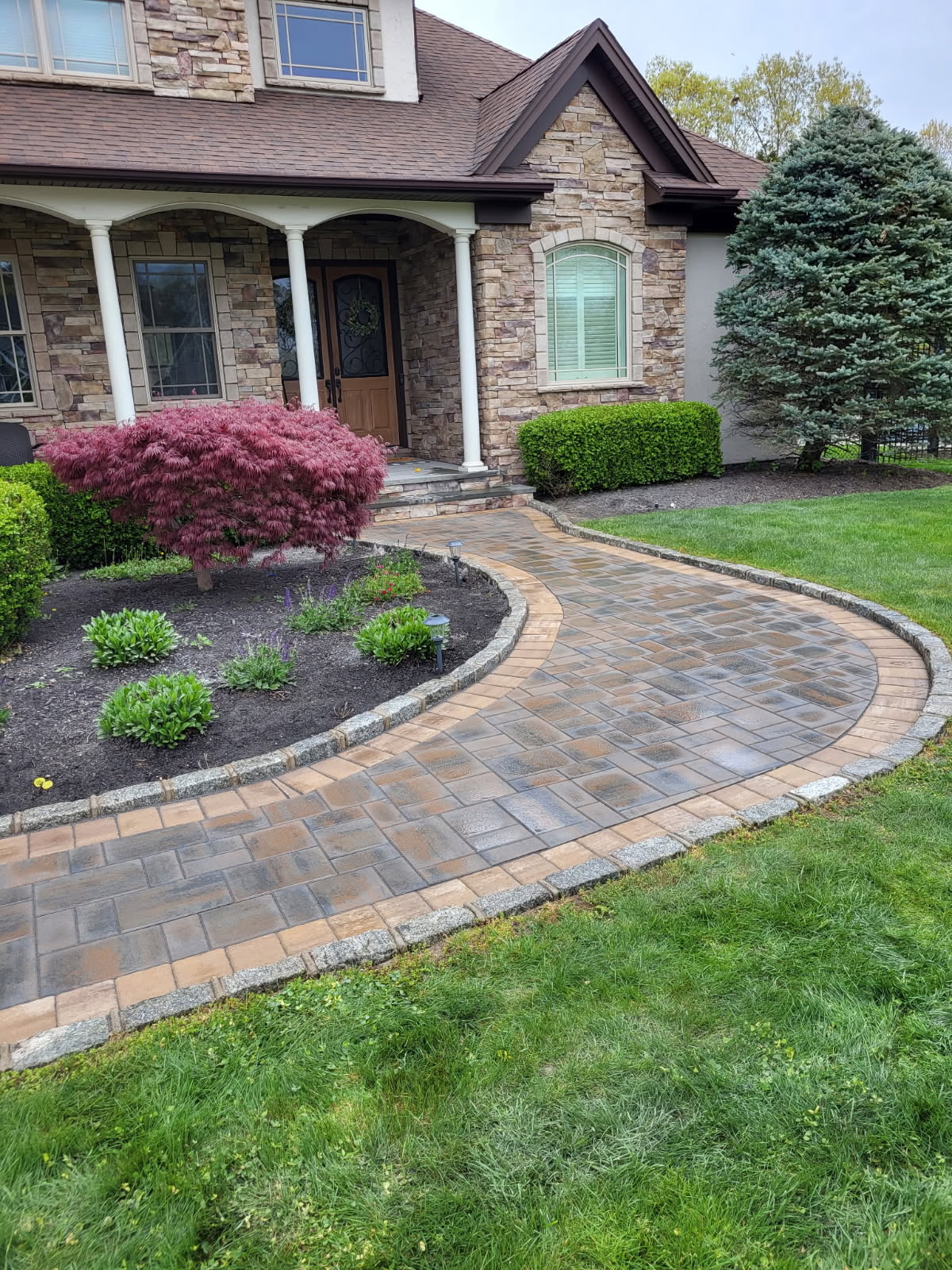 Curved interlocking paver walkway with contrasting border at a Long Island home