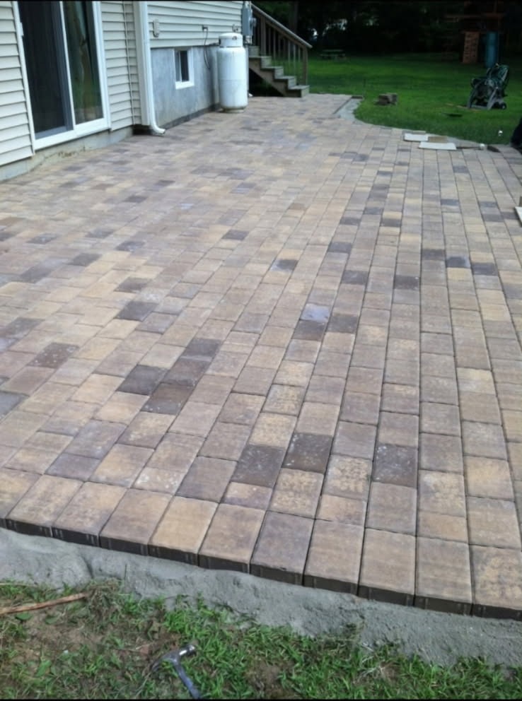 Large multicolor interlocking paver patio installed behind a Long Island home